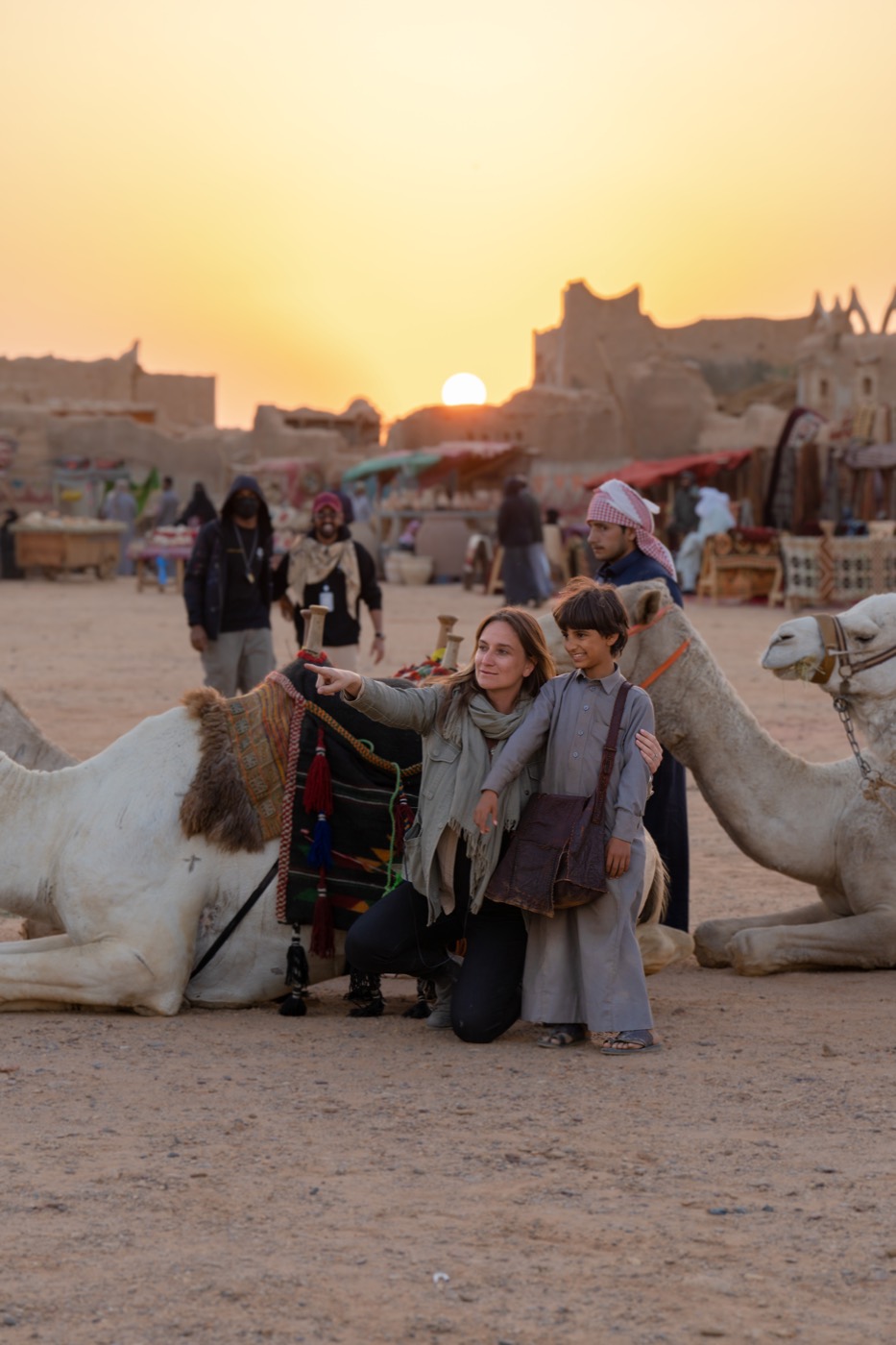 Ashley Avis directing Abdulaziz Alqahtani among camels at sunset
